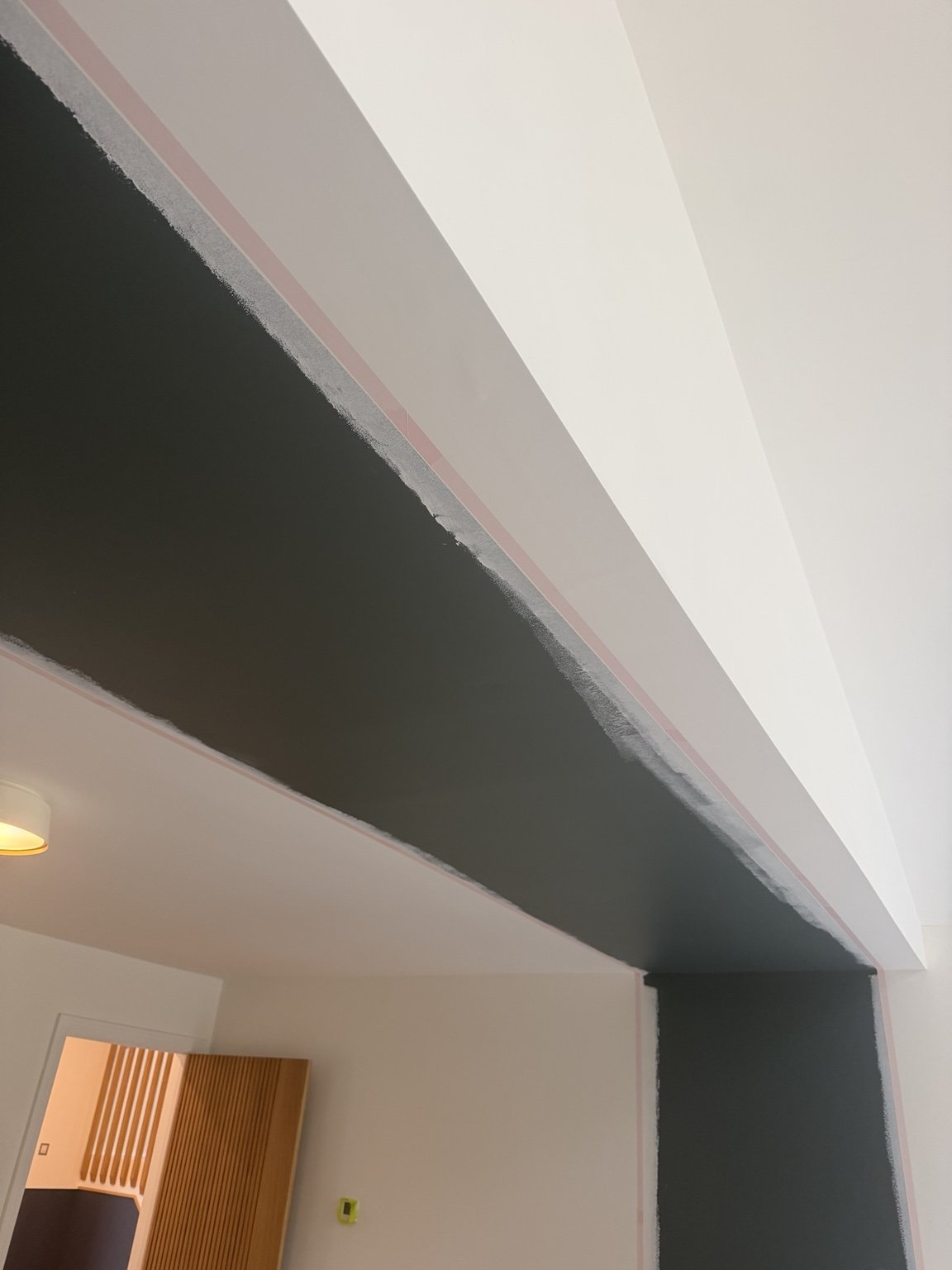 Low-tack tape applied along the ceiling to achieve a straight feature wall paint line